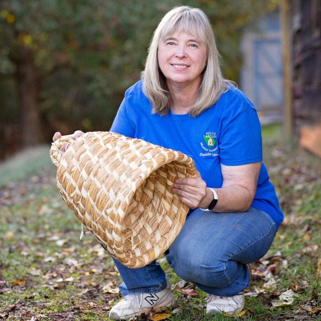 Charlotte Anderson holding a bee skep.