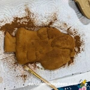 Rubbing powdered cinnamon on beeswax ornament image.