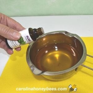 Adding tea tree essential oil to dandelion salve image.