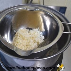 Melting beeswax in a small double boiler insert image.