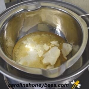 Cocoa butter and coconut oil added to melted beeswax in boiler image.